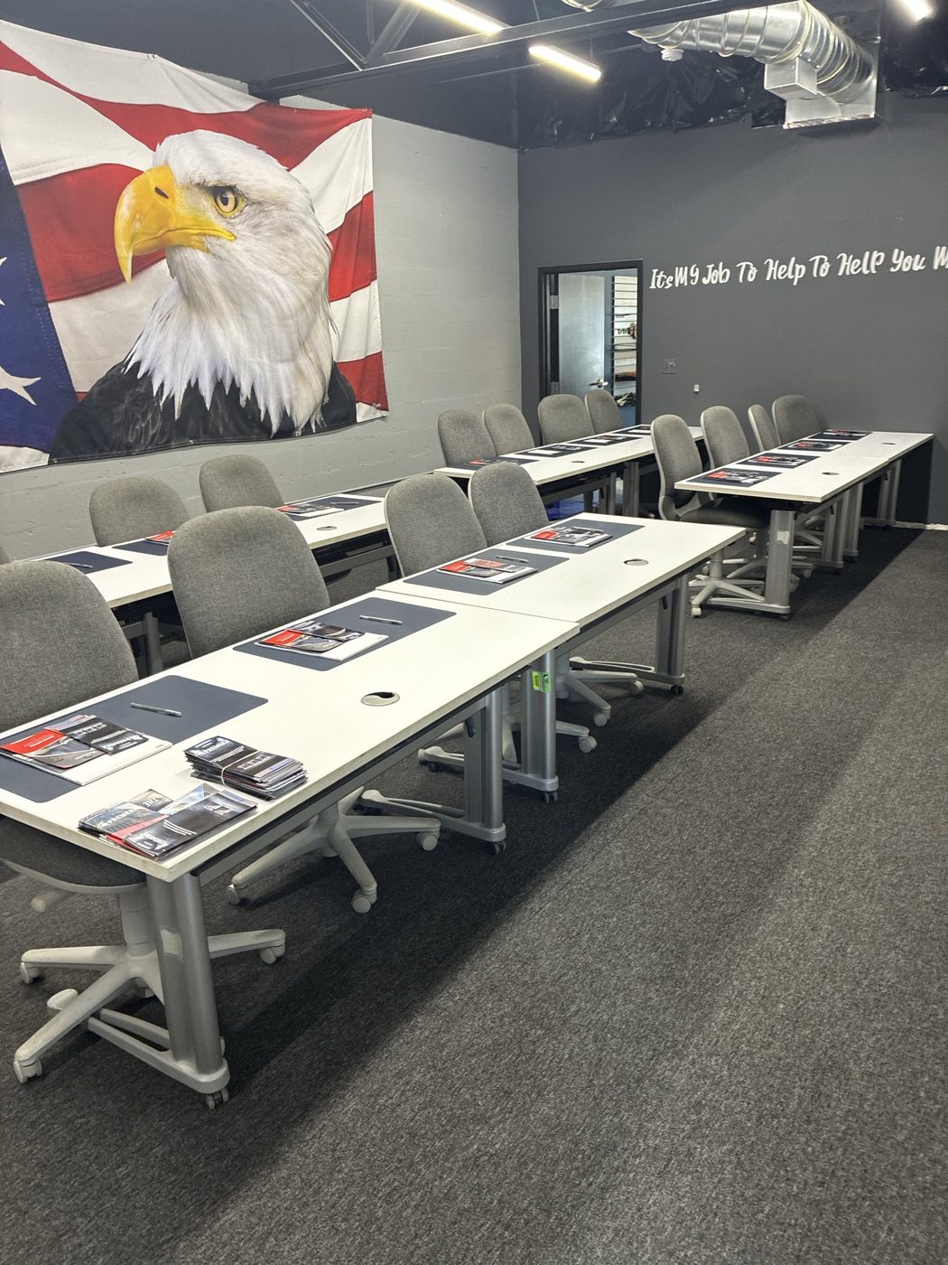 ATC Supply training classroom set up for a session with training materials on each table and a large American flag eagle mural on the wall