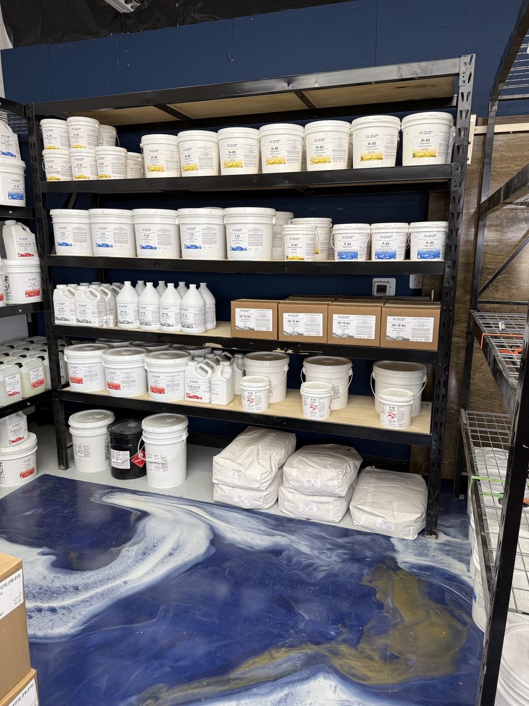 Polymer Nation W-80, P-03, and SP-15 kit shelving with bulk aggregate silica bags stored on the bottom rack over the store's navy metallic floor
